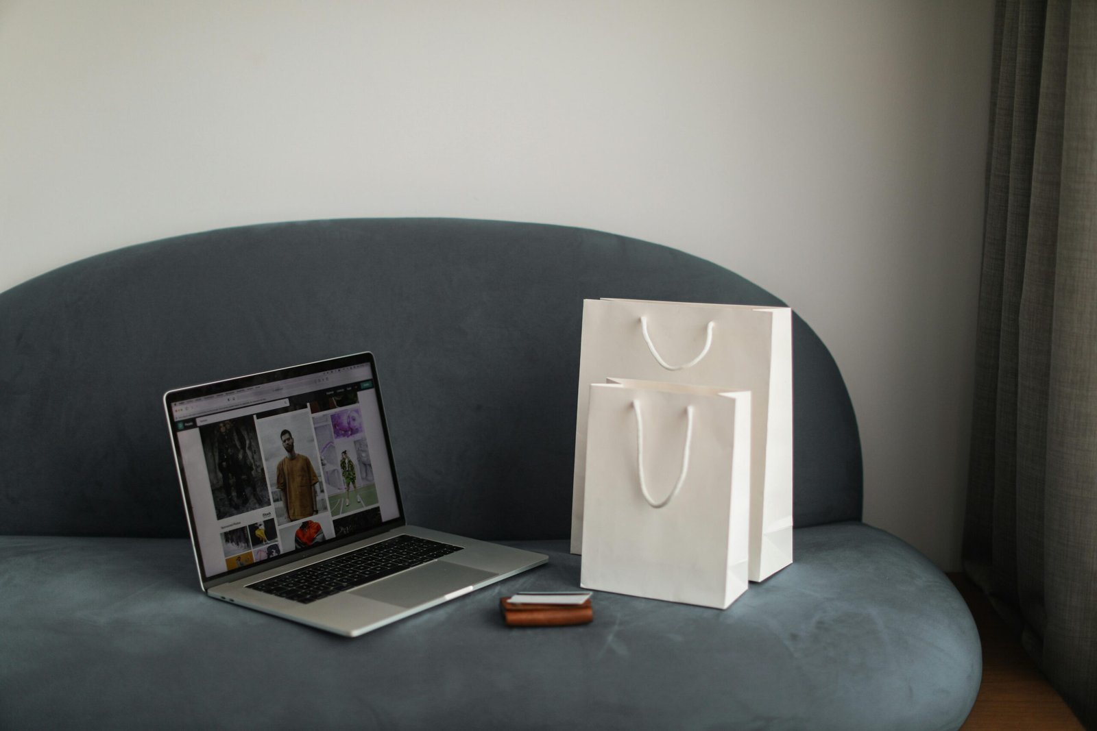 Online winkelen en e-commerce automatisering: laptop met webshop en luxe winkeltassen op een moderne bank.